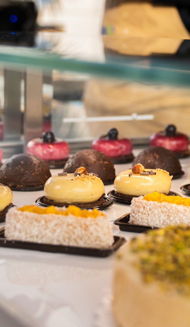 Assortiment de pâtisseries et gâteaux en vitrine, avec tartelettes aux fruits rouges, dômes chocolat et desserts aux ...