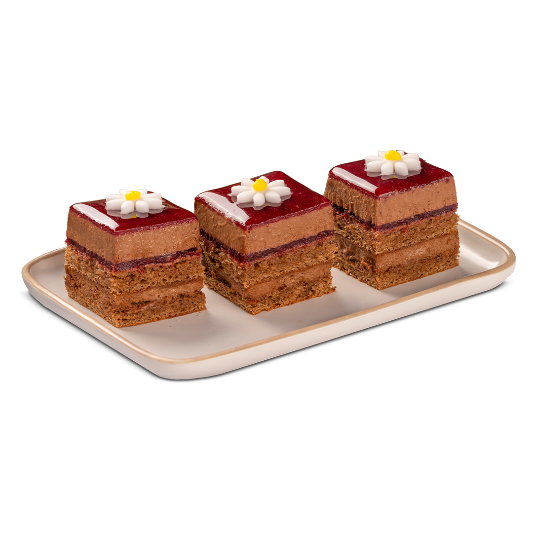 Trois gâteaux au chocolat carrés à étages, glaçage rouge et fleurs en sucre blanches, disposés sur un plateau rectang...