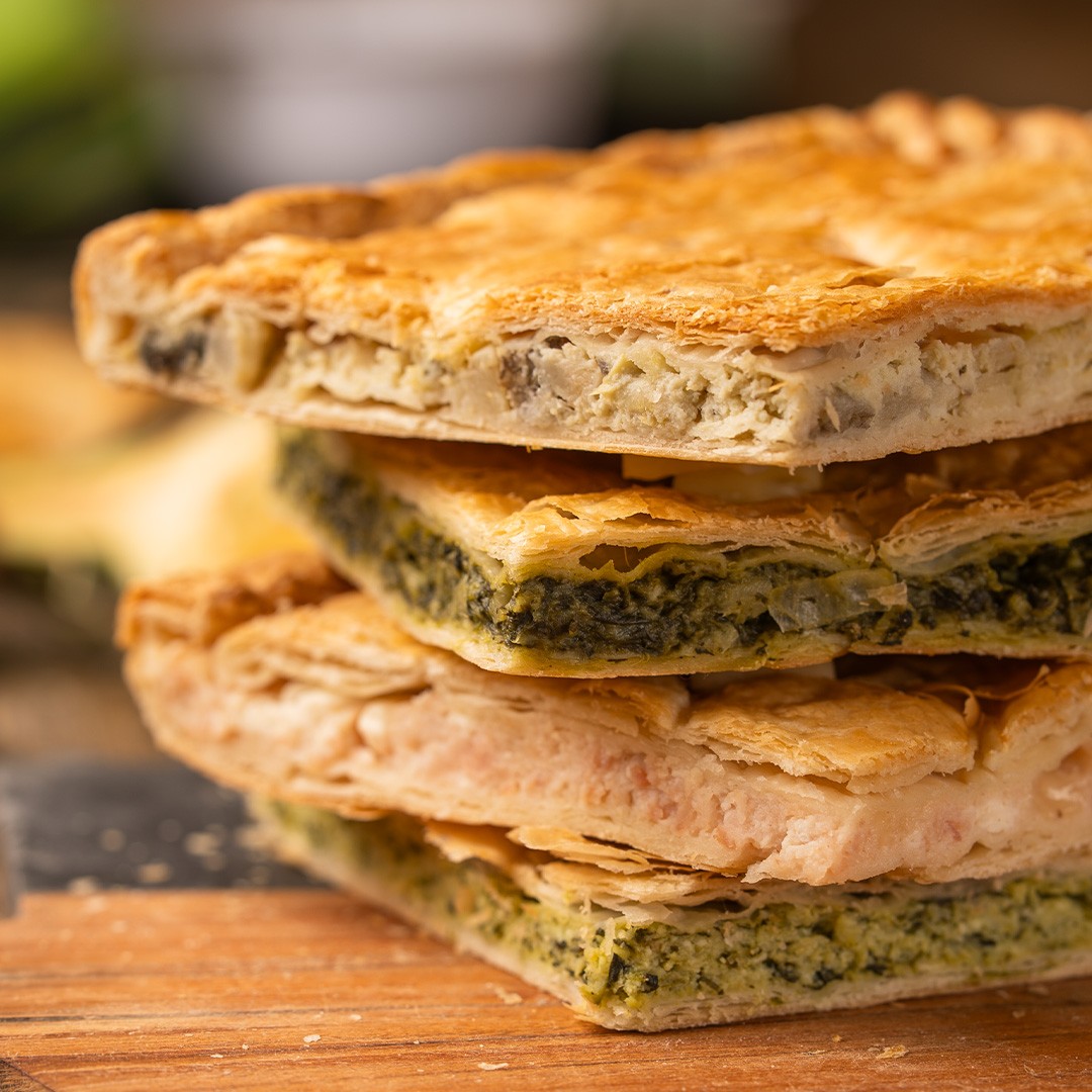 Carrés empilés de pâte feuilletée dorée fourrés aux épinards et fromage crémeux sur planche en bois