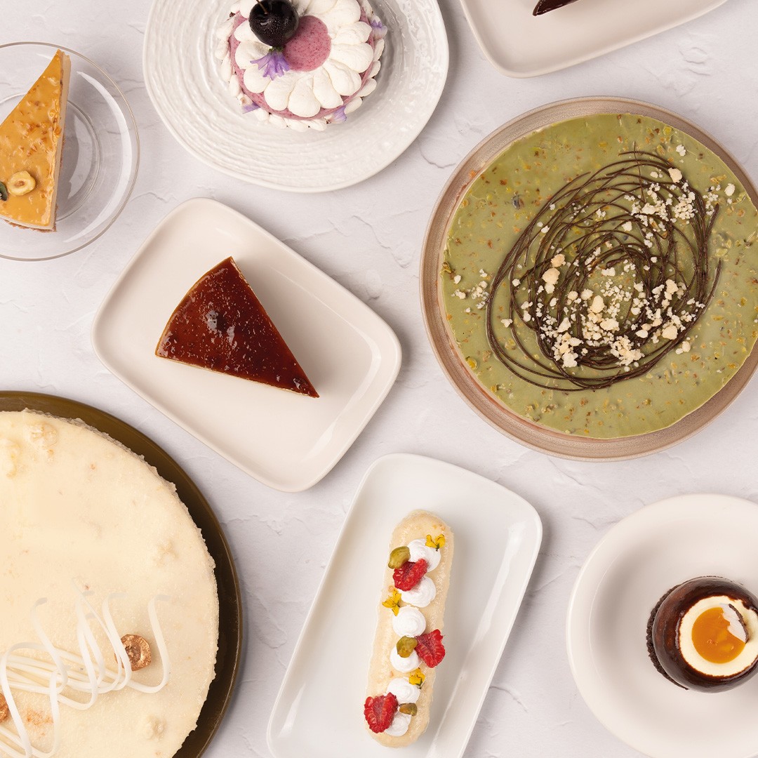 Vue de dessus de desserts variés : cheesecake, flan, tarte à la pistache, éclair et mousse au chocolat en verrines
