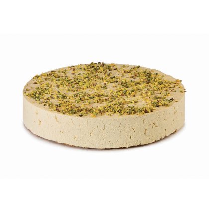 Disque rond de halva pâle garni de pistaches concassées, texture dense et friable, sur fond blanc.