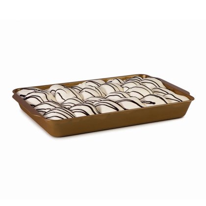 Rangées de pâtisseries glacées blanches nappées de lignes de chocolat noir, disposées sur un plateau doré rectangulaire