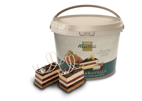 Grand seau de crème à tartiner Master Martini "Aravella" à côté de deux parts de gâteau en couches aux copeaux de cho...