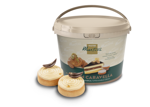 Grand pot de crème à tartiner Master Martini près de deux pâtisseries glacées, copeaux de chocolat et éclats dorés.
