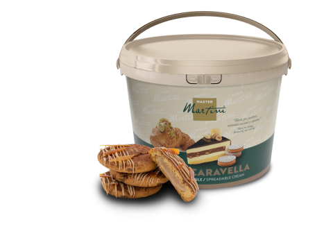 Grand seau de crème à tartiner Master Martini Caravella près de pâtisseries fourrées nappées de chocolat blanc.