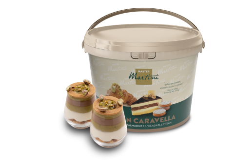 Grand seau de crème à tartiner Master Martini à côté de deux coupes garnies de crème, chocolat et pistache concassée