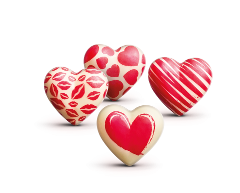 Quatre chocolats blancs en forme de cœur décorés d'empreintes de lèvres rouges, de cœurs, de rayures et d'un motif cœ...