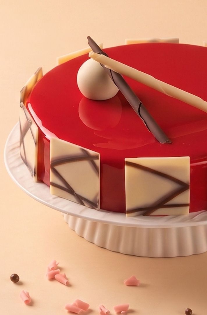 Gâteau rond glaçage miroir rouge brillant, panneaux latéraux en chocolat blanc filet de chocolat noir, décoré d'éclat...