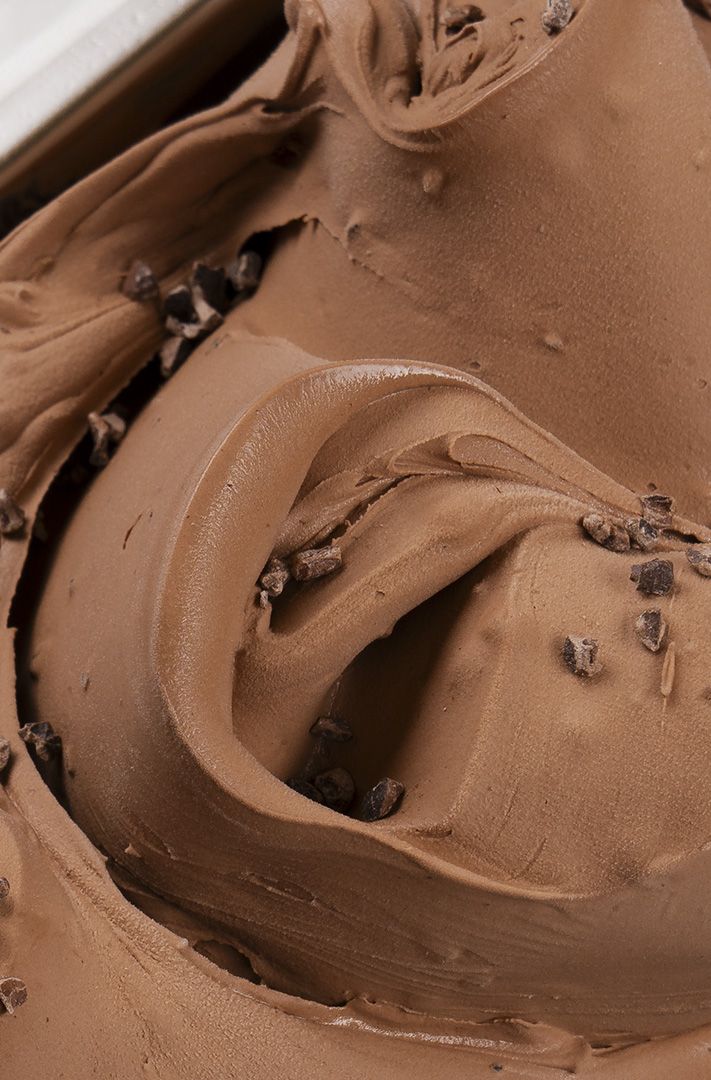 Gros plan sur une glace au chocolat marbrée dans un bac métallique, garnie d'éclats de cacao croquants