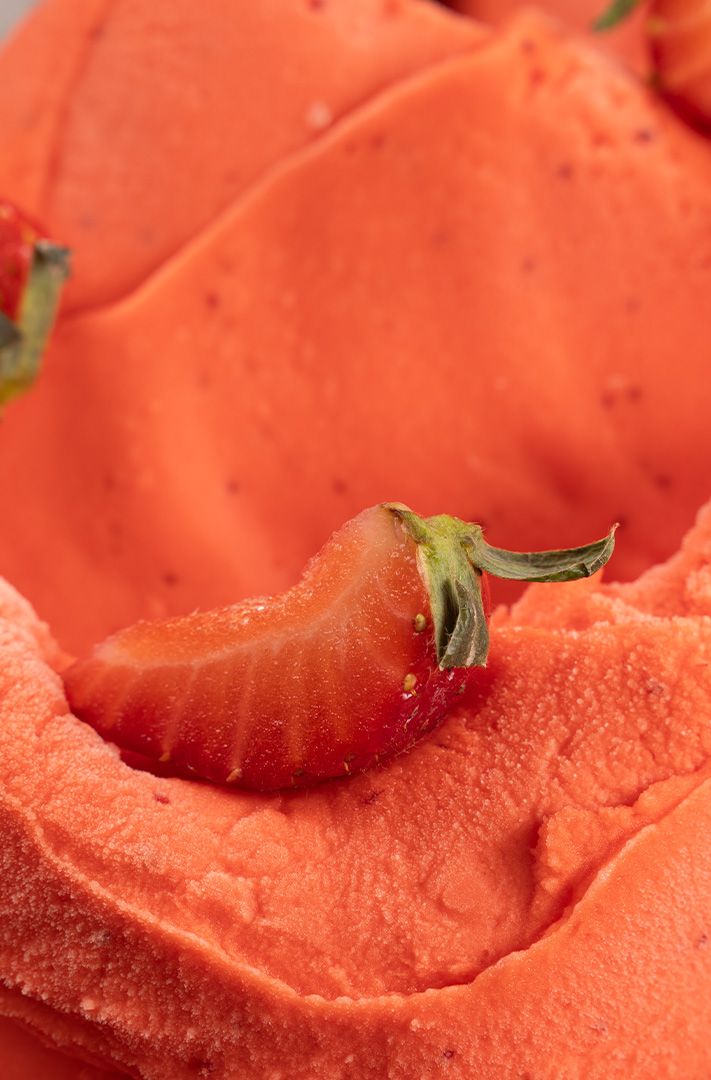 Gros plan sur un sorbet à la fraise orange garni de moitiés et tranches de fraises fraîches