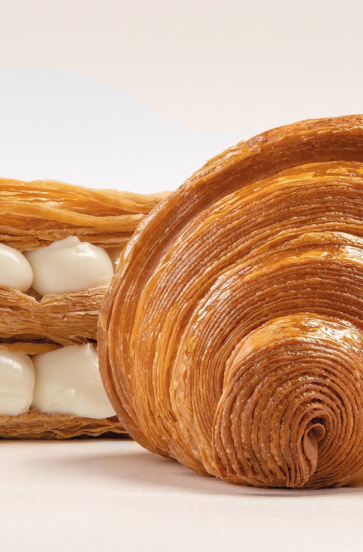 Coupe transversale d'une pâtisserie feuilletée à la crème à côté d'un croissant doré en spirale.