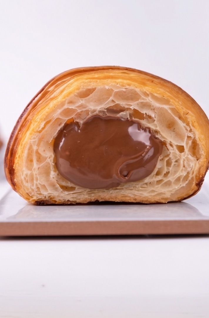 Coupe d'un croissant feuilleté fourré de pâte à tartiner chocolat-noisette brillante