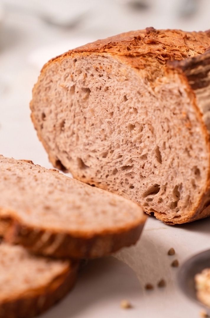 Pain complet tranché à la croûte dorée et croustillante et à la mie aérée, sur une surface claire